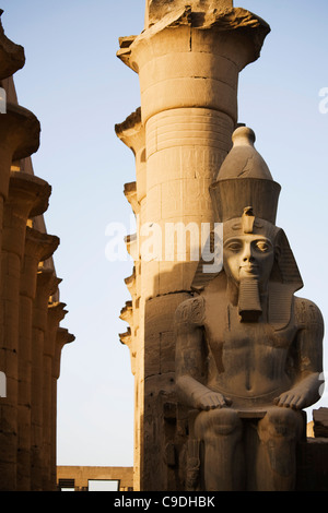 Egitto Luxor Tempio di Luxor, seduto colossale statua di Ramses II e Colonnato di Amenofi III al crepuscolo Foto Stock