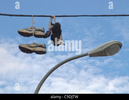 Doble paia di scarpe da ginnastica appese ai lacci delle scarpe da una linea di alimentazione cavo elettrico su sky Palma de Maiorca Spagna Foto Stock