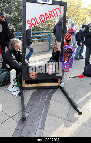 Birmingham, Regno Unito. 30 Novembre, 2011. Una ragazza opera una finta ghigliottina a 'decapitato' Primo Ministro David Cameron e il Vice Primo Ministro Nick Clegg durante le proteste colpendo i lavoratori pubblici in Birmingham. Foto Stock