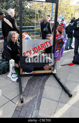 Birmingham, Regno Unito. 30 Novembre, 2011. Una ragazza opera una finta ghigliottina a 'decapitato' Primo Ministro David Cameron e il Vice Primo Ministro Nick Clegg durante le proteste colpendo i lavoratori pubblici in Birmingham. Foto Stock