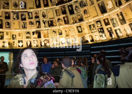 Una femmina di IDF paracadutisti officer guarda verso l'alto nella Sala dei Nomi a Yad Vashem Holocaust Museum, al display di 600 fotografie e frammenti di pagine di testimonianza. Gerusalemme, Israele. 1 dicembre 2011. Foto Stock