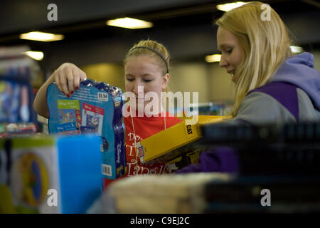 London Ontario, Canada - 8 dicembre 2011. Kaila Swain, sinistra e Emma Beauchamp selezionare giocattoli per riempire un giocattolo di Natale ostacolare al 2011 Esercito della Salvezza giocattolo e unità alimentare centro di distribuzione all'interno del corso la costruzione presso il Western Fiera District. Quest'anno l'Esercito della Salvezza si aspetta per fornire cibo Foto Stock