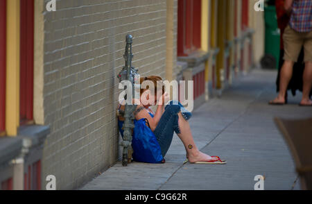 Agosto 5, 2011 - Portland, Oregon, Stati Uniti - una donna sconvolta raccoglie le sue emozioni prima finalmente prendendo un pisolino sul marciapiede nella città vecchia di Portland, Oregon. Portland ospita una vasta popolazione di persone senzatetto e gli spiriti liberi che scratch fuori a vivere sulle strade a causa di esso Foto Stock