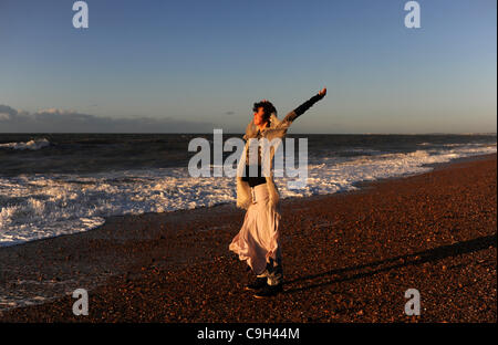 Una giovane donna rende la maggior parte della bellissima alba sulla spiaggia di Brighton dal Molo Ovest a bordo di mare Foto Stock