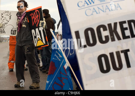 London Ontario, Canada - Gennaio 6, 2012. Anna Wittich detiene due segni come ella Picchetti di fronte alle elettro motrice nella fabbrica di Londra. Electro Motive lavoratori sono stati bloccati da parte della capogruppo - Caterpillar- su Gennaio 1, 2012 dopo che l'Unione europea respinge la società ultima offerta che sarebbe vedere Foto Stock