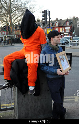 Londra, Regno Unito. Xi gen, 2012. Un manifestante indossando un arancio prigione jump tuta e cappa nera si siede su una scatola di giunzione durante il giorno di Guantànamo di azione. A 8am manifestanti di Turnpike Lane, Londra, sono stati segna il decimo anniversario della apertura della prigione americana camp. Foto Stock