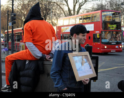 Londra, Regno Unito. Xi gen, 2012. Un manifestante indossando un arancio prigione jump tuta e cappa nera si siede su una scatola di giunzione durante il giorno di Guantànamo di azione. A 8am manifestanti di Turnpike Lane, Londra, sono stati segna il decimo anniversario della apertura della prigione americana camp. Foto Stock