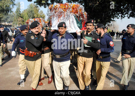 I funzionari di polizia trasportare bare di poliziotti, coloro che sono stati uccisi in un attacco di militanti a Sarband post, per la sepoltura dopo la loro preghiera funebre in corsia di polizia nella città di Peshawar venerdì 13 gennaio, 2012. Foto Stock