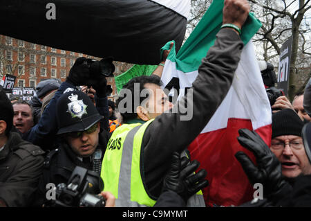 Londra, Regno Unito. 28/01/12. Un anti-Khomeini attivista viene espulso dalla folla da Met della polizia e steward come centinaia di fermare la guerra coalizione manifestanti davanti all'Ambasciata degli Stati Uniti a Londra. Foto Stock