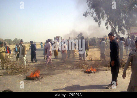 Manifestanti arrabbiati bruciare pneumatici Larkana-Sukkur blocco di strada durante la manifestazione di protesta dei residenti del villaggio di Agani contro il mancato pagamento della seconda rata del Watan Card in Naudero Lunedì, 13 febbraio 2012. Foto Stock