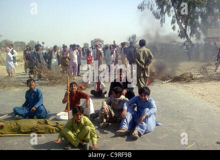 Manifestanti arrabbiati bruciare pneumatici Larkana-Sukkur blocco di strada durante la manifestazione di protesta dei residenti del villaggio di Agani contro il mancato pagamento della seconda rata del Watan Card in Naudero Lunedì, 13 febbraio 2012. Foto Stock