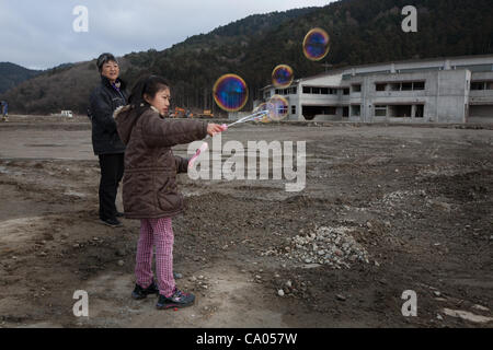 Hiroko Oyama e nipote Hikari rilasciare bolle in aria ( "come tutti i bambini come bolle') per le memorie dei 74 bambini che hanno perso la loro vita in Okawa Scuola Elementare, nella pianura fangosa dove una volta sorgeva la comunità di Kamaya, sul 1 anno di anniversario del 11 marzo 2011 eart Foto Stock
