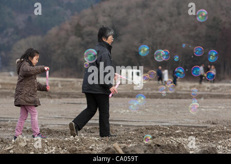 Hiroko Oyama e nipote Hikari rilasciare bolle in aria per le memorie dei 74 bambini che hanno perso la loro vita in Okawa Scuola Elementare, nella pianura fangosa dove una volta sorgeva la comunità di Kamaya, sul 1 ° anniversario dell'11 marzo 2011 il terremoto e lo tsunami, in Kamaya, Toh Foto Stock