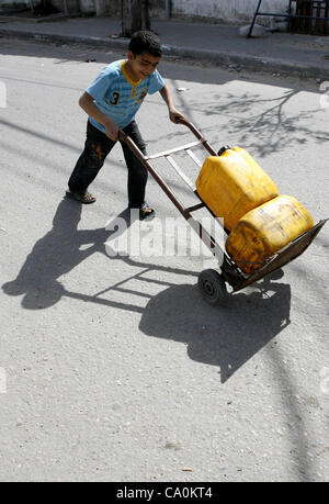 Marzo 14, 2012 - Rafah nella striscia di Gaza, Territori palestinesi - bambini palestinesi il riempimento di bottiglie di plastica con acqua potabile da un pubblico tocca all'Ente soccorso e lavori delle Nazioni Unite (UNRWA) sede nel sud della striscia di Gaza un campo di rifugiati di Rafah il 14 marzo 2012. Foto Stock