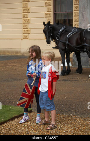 Isola di Wight, Hampshire, Regno Unito domenica 3 giugno 2012. Celebrazioni del Giubileo a Osborne House con la Regina Vittoria. Giovane ragazzo e ragazza che tiene la borsa Union Jack in posa davanti ai cavalli Foto Stock