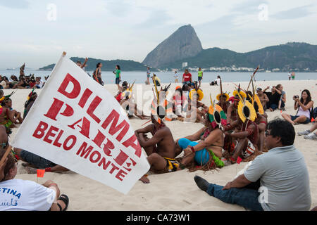 I popoli indigeni e gli altri stanno cominciando ad assemblare il banner umana sulla spiaggia Flamengo con lo Sugarloaf in background per protestare contro la costruzione di dighe idroelettriche sul Brasile i fiumi. Un partecipante porta una bandiera, 'Dilma Pare Belo Monte" - "ilma [al presidente del Brasile] smettere di Belo Monte". Il popolo del Vertice alla Conferenza delle Nazioni Unite sullo Sviluppo Sostenibile (Rio+20), Rio de Janeiro, Brasile, 19 giugno 2012. Foto © Sue Cunningham. Foto Stock