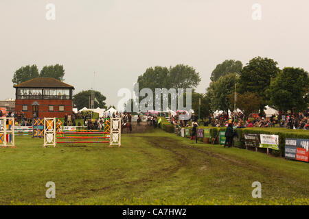 Il imbevuto di acqua arena principale con tracce di pneumatici dal trattore parade. Cavalli attendere per prendere parte in show jumping, spettatori attendere vicino come il sole esce sul Giovedi 21 giugno 2012 a Lincoln, Regno Unito. Foto Stock