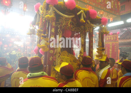 Samut Sakhon Provincia, Thailandia, 26 Giugno, 2012 . Gli uomini della città porta pilastro torna nel tempio. Il Chaopho Lak Mueang processione o Santuario della Parata City-God avviene nel mese di giugno di ogni anno al terrapieno di fronte al municipio. Il 'Chaopho Lak Mueang' viene quindi posto in un palanquin su una barca da pesca che è splendidamente decorato con bandiere e fatto galleggiare lungo la Tha Mento River da Talat Maha Chai di Tha Chalom nella zona di Wat Suwannaram e ulteriormente al Wat Chong Lom, fornendo una opportunità per il popolo a pagare il rispetto e il guadagno di buona fortuna. Foto Stock