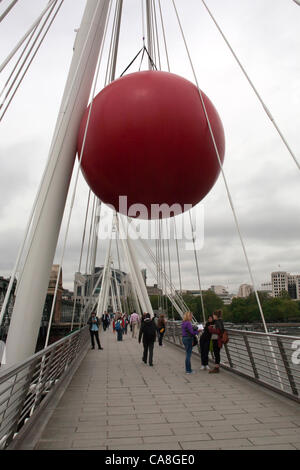 La sfera rossa progetto arriva in centro a Londra il 27 giugno 2012. Il progetto ha viaggiato per il Regno Unito e a Londra fino al 1° luglio 2012. Il progetto è l idea del pittore e scultore Kurt Perschke oggi era appeso sul ponte del Giubileo di fronte la stazione di Charing Cross. Foto Stock