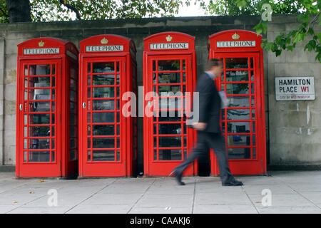 Set 25, 2003; Londra, UK; un uomo d affari passeggiate negli ultimi 4 British Royal red telefoni pubblici a pagamento nelle caselle sulla Hamilton Place nel centro di Londra. Il Publifon rosso un famoso simbolo di Gran Bretagna. La città metropolitana di Londra è una delle città più famose in Europa e attrae migliaia di turisti e Foto Stock