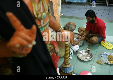 KUALA LUMPUR, Malesia febbraio , 2004 25 anno Gunasegran, prima volta partecipante i8n il festival, riceve la benedizione per la protezione dal sacerdote Indù presso il suo tempio nel centro cittadino di Kuala Lumpur alla vigilia del festival di Thaipusam 4 febbraio. 2004. Trenta o più giorni di digiuno e di ore di rendere C Foto Stock