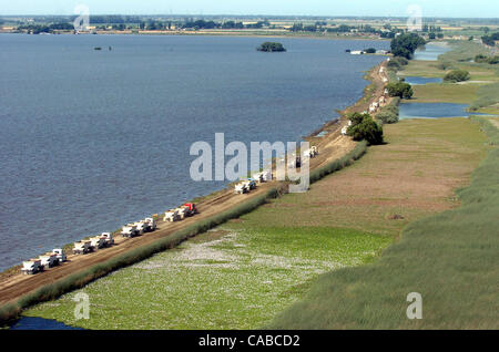 I carrelli haul sporco e rocce lungo Trapper Slough per essere utilizzato nelle speranze di fermare le acque di esondazione (a sinistra) da ottenere per l'autostrada 4 (angolo superiore destro e che corre parallela al slough) vicino superiore tratto Jones in San Joaquin County, California, sabato 5 giugno 2004. (Dean Coppola/Contra Costa Times) Foto Stock