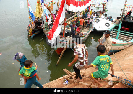 Gli abitanti di un villaggio al villaggio fisheman board sulla barca durante un pescatore alms cerimonia del mare o Tradisi Nyadran nella lingua locale in Marunda periferia di Jakarta, luglio 25, 2010.Tradisi Nyadran è una tradizione della comunità costiere è un simbolo del rapporto con gli antenati, colleghi, Dio e l'universo, come Foto Stock