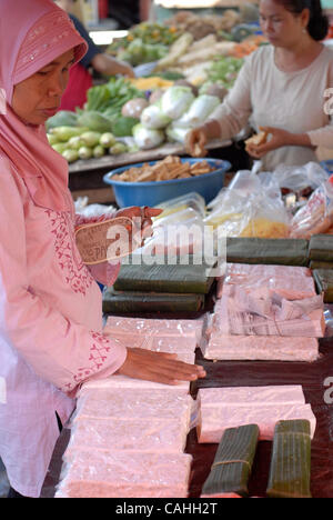 19 gennaio 2007 Jakarta, Indonesia La Sig.ra Ayo tocca un bar di tempeh in attesa per il suo ordine presso un distributore in stallo al Pedok Street Market in area Tebet, a sud di Giacarta. I prodotti di soia sono un ingrediente essenziale nella cucina asiatica così come cibo di graffa per la regione?s poveri. Per molti Indonesia Foto Stock