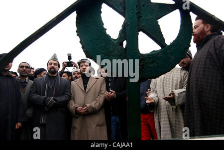 Kashmir il sommo sacerdote e presidente della sua fazione di tutte le parti Hurriyat (Libertà) Conferenza (APHC) Mirwaiz Umar Farooq (in cappotto nero) e Senior leader indipendentista e presidente della libertà democratiche partito, Shabir Ahmad Shah sono visibili attraverso una mezzaluna in acciaio e una stella eretto su una tomba come essi Foto Stock