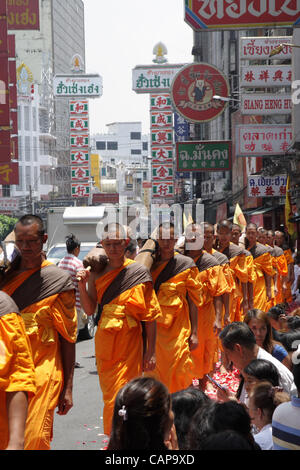 Bangkok, Tailandia. 05 aprile 2012. I monaci tailandesi a piedi su petali di rose da devoti. Più di un migliaio di monaci di Wat Phra Dhammakaya stanno prendendo parte ad un pellegrinaggio , a piedi attraverso zone interne di Bangkok, che conduce alla critica che è improprio e causare problemi per il traffico. Foto Stock