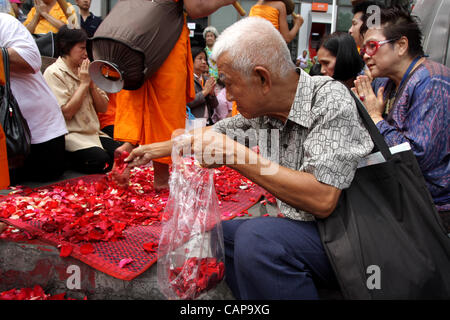 Bangkok, Tailandia. 05 aprile 2012. I monaci tailandesi a piedi su petali di rose da devoti. Più di un migliaio di monaci di Wat Phra Dhammakaya stanno prendendo parte ad un pellegrinaggio , a piedi attraverso zone interne di Bangkok, che conduce alla critica che è improprio e causare problemi per il traffico. Foto Stock