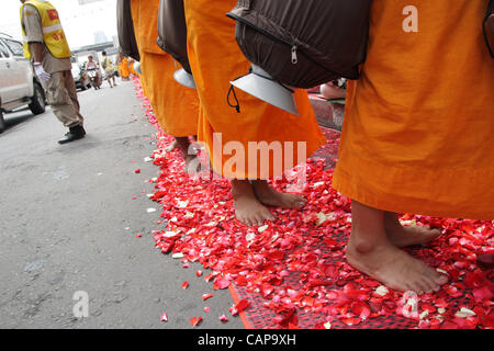 Bangkok, Tailandia. 05 aprile 2012. I monaci tailandesi a piedi su petali di rose da devoti. Più di un migliaio di monaci di Wat Phra Dhammakaya stanno prendendo parte ad un pellegrinaggio , a piedi attraverso zone interne di Bangkok, che conduce alla critica che è improprio e causare problemi per il traffico. Foto Stock