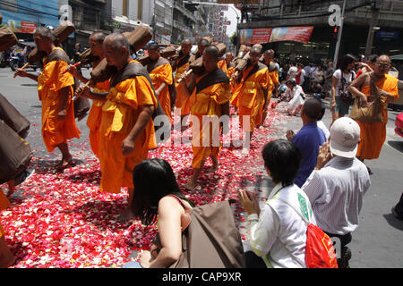 Bangkok, Tailandia. 05 aprile 2012. I monaci tailandesi a piedi su petali di rose da devoti. Più di un migliaio di monaci di Wat Phra Dhammakaya stanno prendendo parte ad un pellegrinaggio , a piedi attraverso zone interne di Bangkok, che conduce alla critica che è improprio e causare problemi per il traffico. Foto Stock