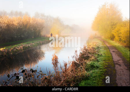 Camminatori solitari lungo il vecchio canale nelle prime ore del mattino la molla di nebbia, Newport Shropshire, Regno Unito Foto Stock