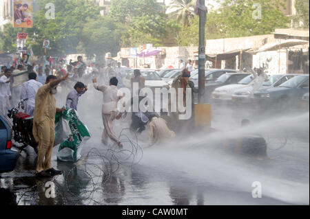 I manifestanti gridare slogan come polizia usa acqua-canon-veicolo per disperderlo durante una manifestazione di protesta della commissione nazionale per lo sviluppo umano (NCHD) dipendenti per i lavori regolari, a Karachi il lunedì, 23 aprile 2012. Foto Stock