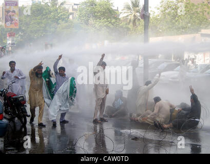 I manifestanti gridare slogan come polizia usa acqua-canon-veicolo per disperderlo durante una manifestazione di protesta della commissione nazionale per lo sviluppo umano (NCHD) dipendenti per i lavori regolari, a Karachi il lunedì, 23 aprile 2012. Foto Stock