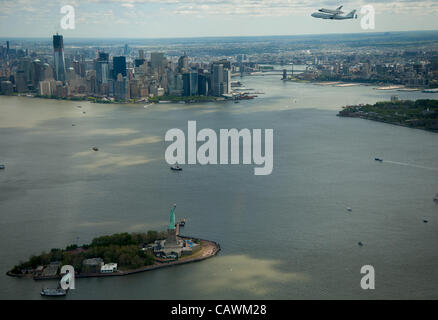 Lo Space Shuttle Enterprise, montata in cima ad un NASA 747 vettore navetta di aeromobili (SCA), è visto come vola vicino alla statua della libertà e dello skyline di Manhattan, Venerdì, Aprile 27, 2012 a New York. Enterprise è stata la prima navetta orbiter costruito per la NASA eseguendo voli di prova in atmosfera e mi è stato Foto Stock