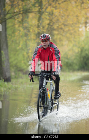 Il 1° maggio 2012, Billericay, Essex, Regno Unito. Ciclista viaggia attraverso acque alluvionali. Una pioggia torrenziale ha portato ad allagamento locale che è diventata peggio anche se la pioggia ha interrotto a causa di run-off da campi circostanti. Foto Stock