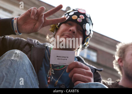 Londra, UK, 01/05/12. Mayday dimostranti marzo su Londra. Un occupare protestor siede sulla cima di fermata autobus vicino a Trafalgar square in possesso di una carta lettura "Benvenuto a occupare'. Foto Stock