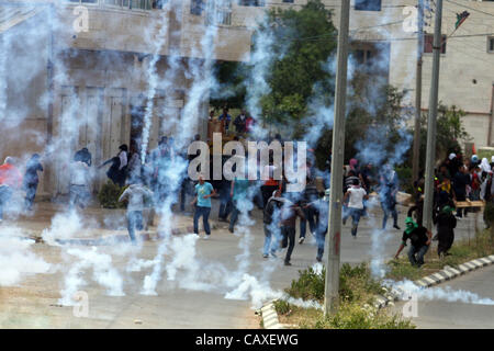 3 maggio 2012 - Ramallah, West Bank, Territorio palestinese - gas lacrimogeni sparati dalle truppe israeliane riempie l'aria nei pressi di pietra palestinese-tubi espulsori durante scontri accanto ai militari israeliani prigione di Ofer, vicino a Beitunia, West Bank. I manifestanti sono stati agendo in solidarietà con i prigionieri palestinesi in Israe Foto Stock