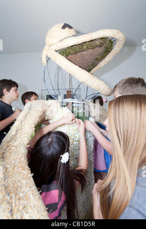 I bambini lavorano insieme per decorare le sculture di filo con narciso e per fare in modo che siano pronti per la parata del 53 Festival di narciso, Bad Aussee, Ausseerland, Stiria, Austria, Sabato 19 Maggio, 2012. Foto Stock