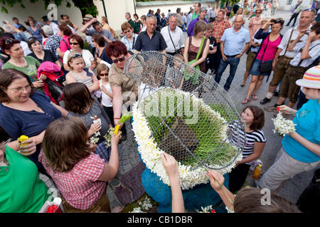 I turisti e la gente del posto e i giovani e i vecchi, lavorano insieme per decorare le sculture di filo con narciso e per fare in modo che siano pronti per la parata del 53 Festival di narciso, Bad Aussee, Ausseerland, Stiria, Austria, Sabato 19 Maggio, 2012. Foto Stock