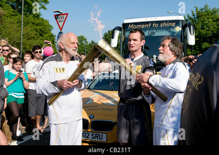 Torcia olimpica team a Longwell Green, Bristol, Regno Unito, 2012 come i due portacolori di invertire i ruoli e la luce della nuova torcia. Foto Stock