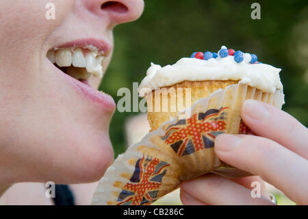 Close up della donna mangiare cupcake decorato con una unione jack tema nella celebrazione dei Giochi olimpici e regine giubileo. Foto Stock