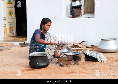 Giovani indiani moglie in un villaggio rurale facendo chapati su un fuoco aperto al di fuori di casa sua. Andhra Pradesh, India Foto Stock