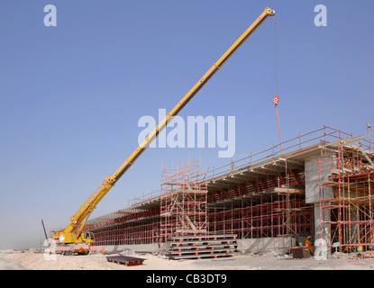 Una gru mobile opera su una strada sito in costruzione a Dubai. Parte della nuova strada parallela schema Foto Stock