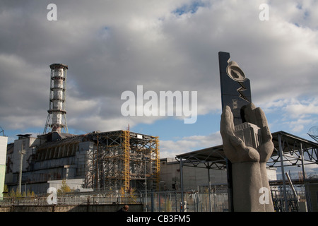 Memoriale per i liquidatori di Chernobyl con reattore numero 4 in background, la centrale di Cernobyl in Ucraina Foto Stock