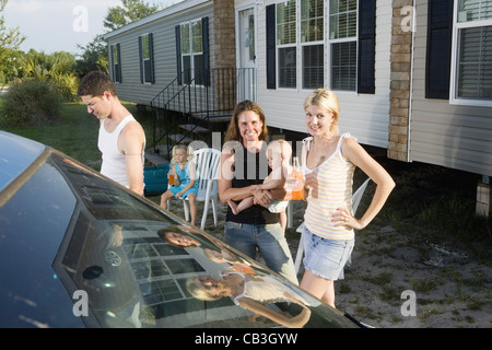 La famiglia e gli amici in piedi accanto a auto al di fuori del rimorchio home Foto Stock