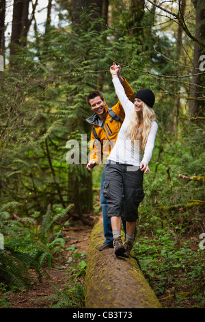 Portland, Oregon, Stati Uniti d'America, giovane camminando lungo il log in foresta Foto Stock