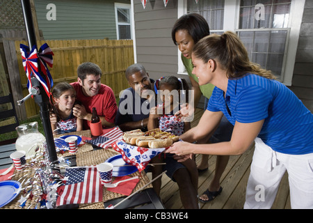 Due famiglie su backyard patio godendo un cookout il 4 luglio Foto Stock